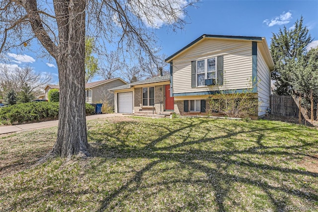 tri-level home featuring a front yard, brick siding, fence, concrete driveway, and an attached garage