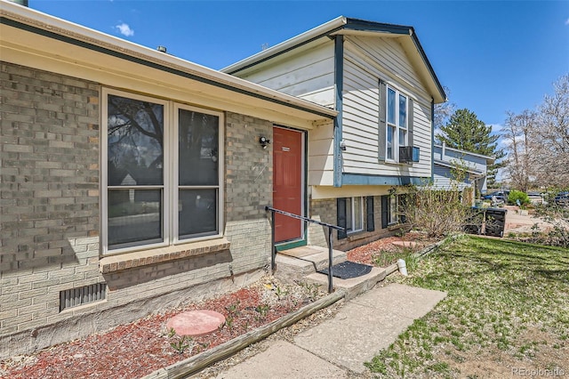 view of front of property featuring entry steps, a front lawn, and brick siding