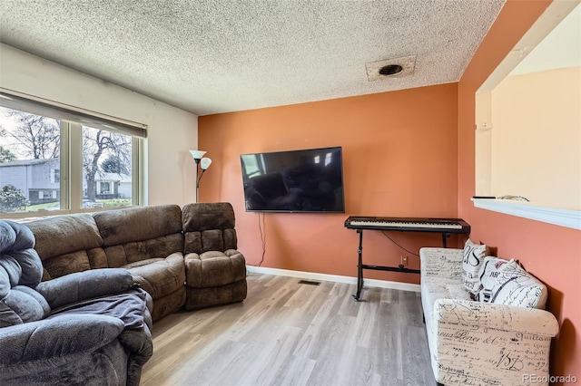 living room featuring a textured ceiling, visible vents, and wood finished floors