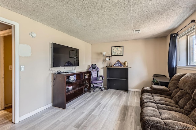 living room featuring a textured ceiling, baseboards, wood finished floors, and visible vents