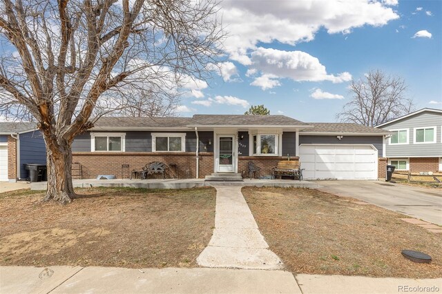 view of front of home featuring driveway, an attached garage, and brick siding