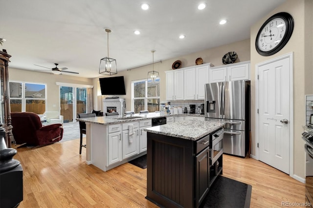 kitchen with white cabinetry, stainless steel fridge, sink, and a kitchen island