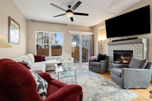 living room featuring a brick fireplace, ceiling fan, and light hardwood / wood-style flooring