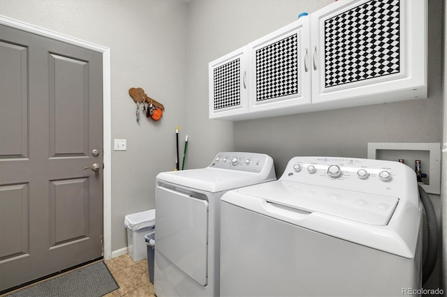 clothes washing area with cabinets, washer and dryer, and light tile patterned floors