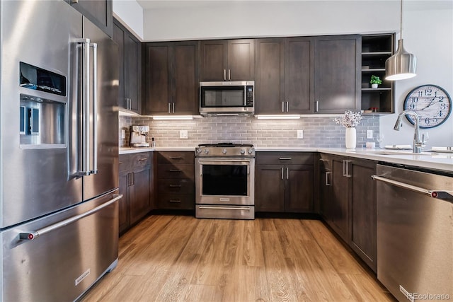 kitchen with sink, hanging light fixtures, light hardwood / wood-style flooring, dark brown cabinetry, and stainless steel appliances