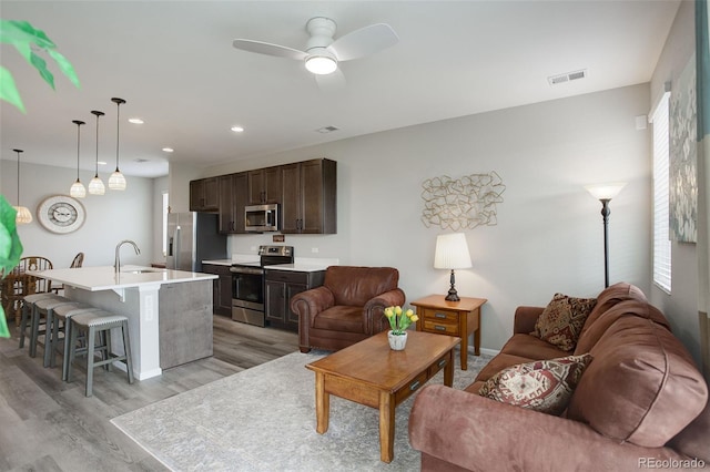 living room featuring light hardwood / wood-style floors, sink, and ceiling fan