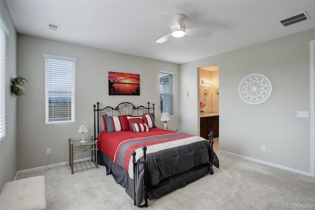 bedroom with ceiling fan, ensuite bath, and light colored carpet