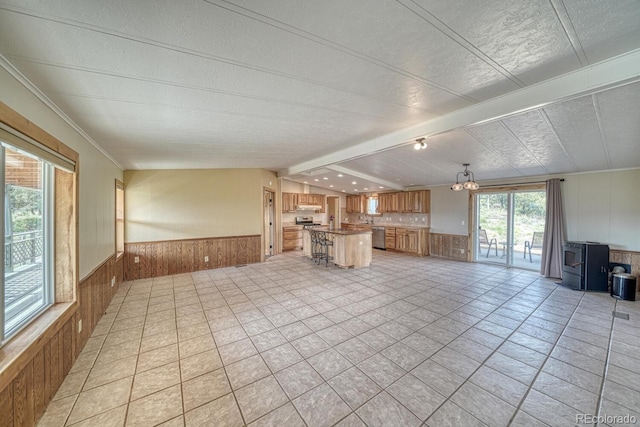 236 Boreen Way, Howard, CO 81233 - unfurnished living room featuring wooden walls, a wainscoted wall, beam ceiling, a chandelier, and a wood stove