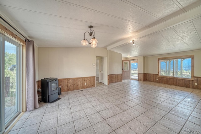 236 Boreen Way, Howard, CO 81233 - empty room with wainscoting, a wood stove, wooden walls, a chandelier, and light tile patterned floors
