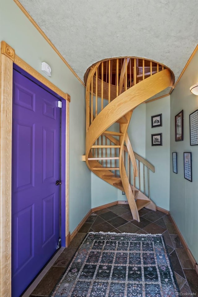 foyer with stairway, baseboards, ornamental molding, and stone tile floors