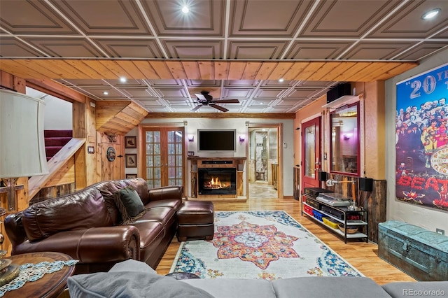 living area with wood finished floors, a ceiling fan, an ornate ceiling, a warm lit fireplace, and recessed lighting