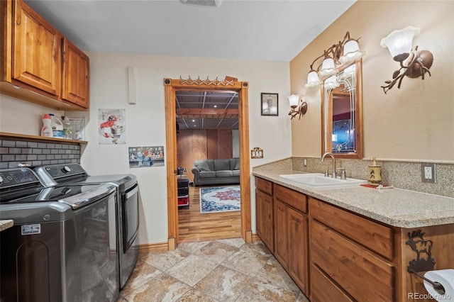 washroom with stone finish flooring, washing machine and dryer, cabinet space, and a sink