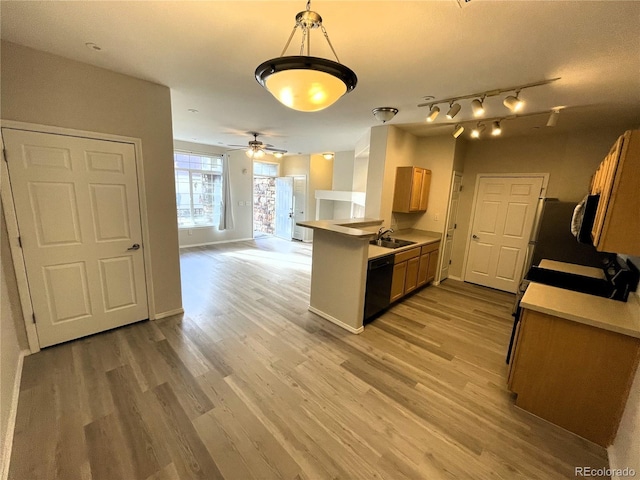 kitchen featuring light wood-type flooring, a sink, black dishwasher, a peninsula, and light countertops