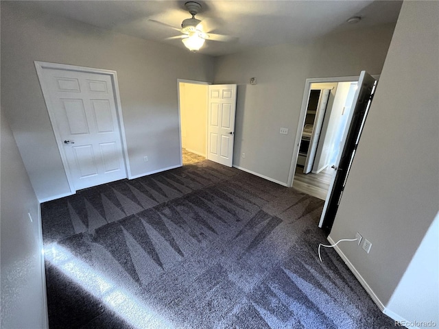 unfurnished bedroom featuring dark colored carpet, baseboards, and a ceiling fan