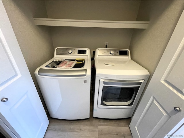 clothes washing area with washer and dryer, laundry area, and wood finished floors