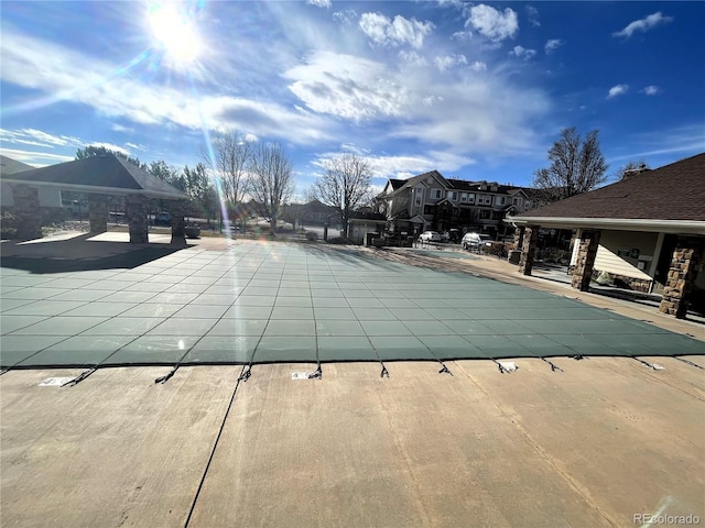 community pool with a residential view and a patio area