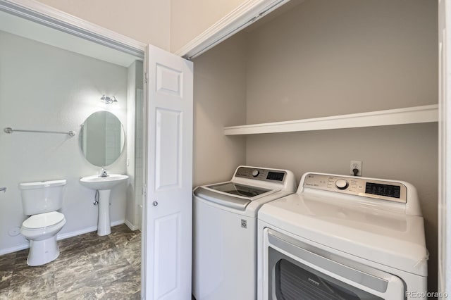 laundry room featuring washing machine and clothes dryer, laundry area, baseboards, and a sink