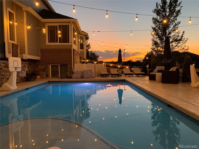 pool at dusk featuring outdoor lounge area and a patio