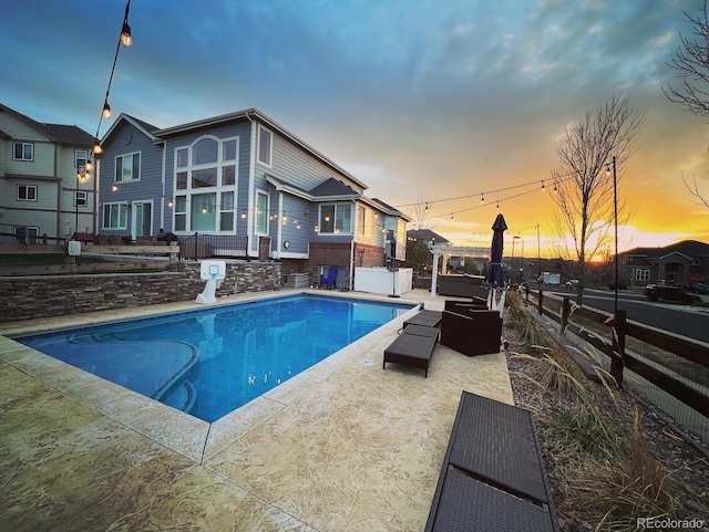 pool at dusk featuring an outdoor hangout area and a patio