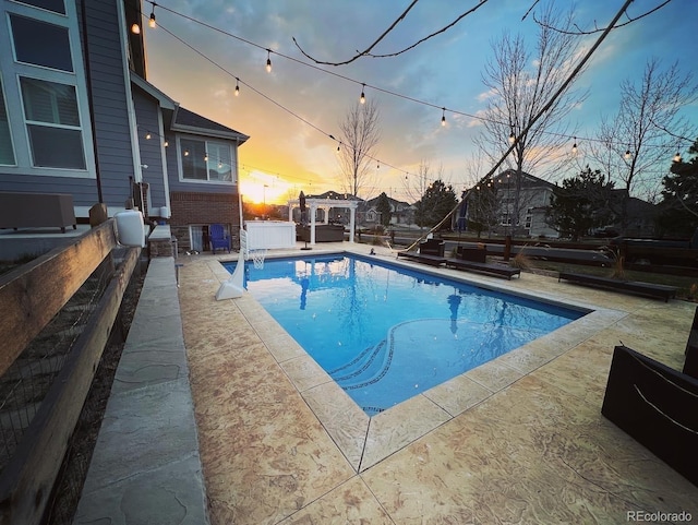 pool at dusk featuring a patio