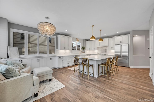 kitchen featuring hanging light fixtures, white cabinetry, a center island, and stainless steel built in fridge