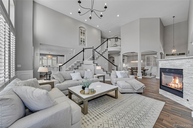 living room with an inviting chandelier, hardwood / wood-style flooring, and a high ceiling