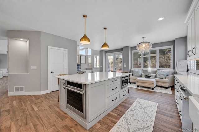 kitchen with pendant lighting, oven, white cabinets, and a kitchen island