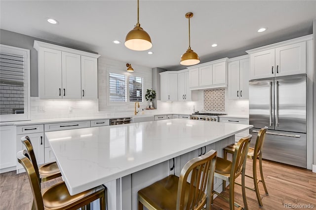 kitchen with tasteful backsplash, recessed lighting, white cabinetry, a kitchen island, and appliances with stainless steel finishes