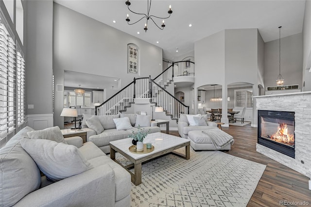 living area with wood finished floors, a towering ceiling, stairway, arched walkways, and a notable chandelier