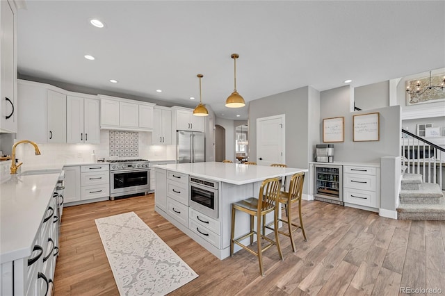 kitchen featuring wine cooler, light wood-style flooring, a sink, decorative backsplash, and high quality appliances