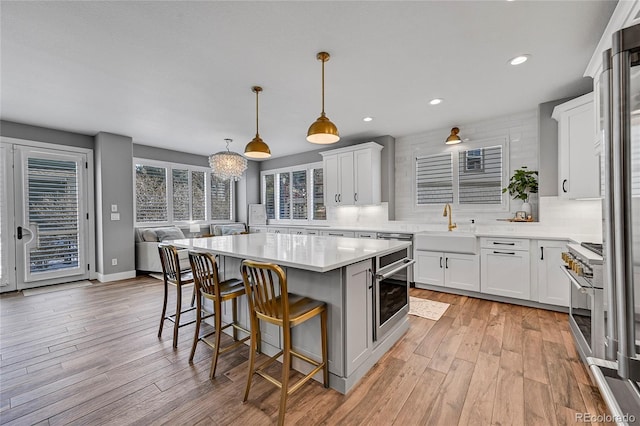 kitchen with a sink, stainless steel appliances, a kitchen breakfast bar, backsplash, and light countertops