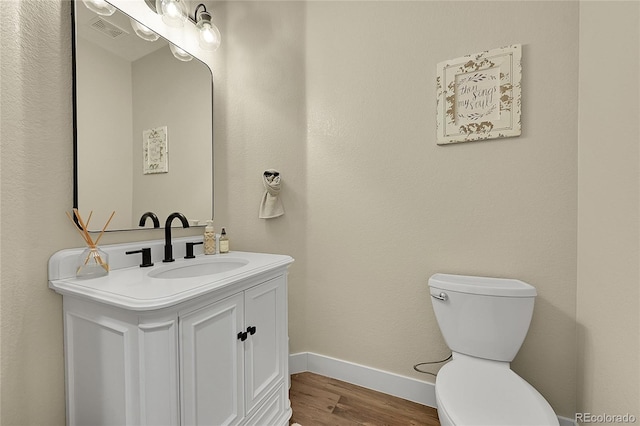 bathroom with toilet, wood finished floors, vanity, visible vents, and baseboards