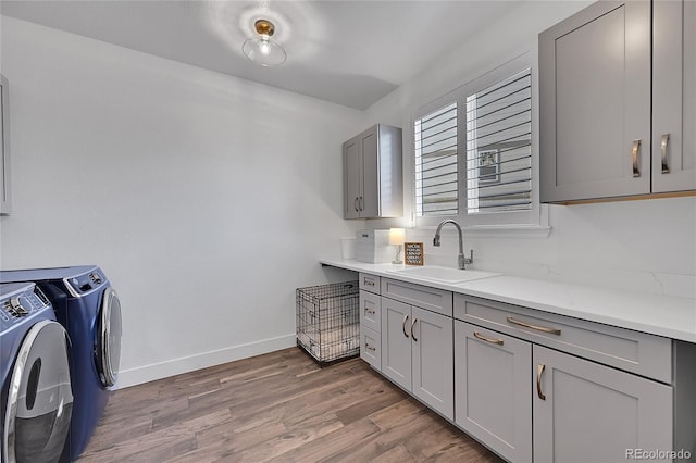 interior space featuring separate washer and dryer, gray cabinetry, wood finished floors, and a sink