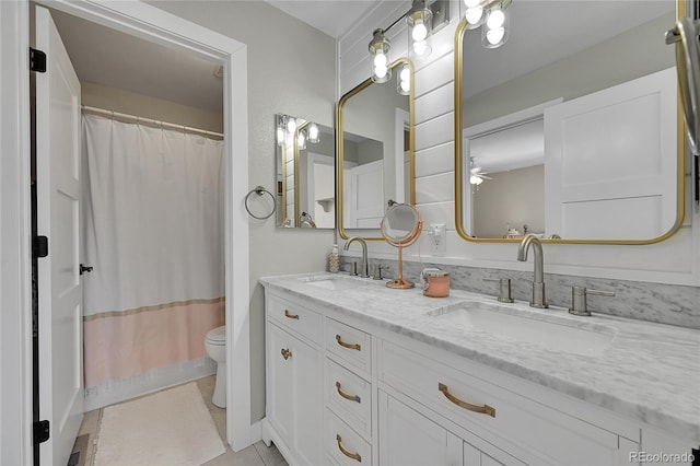 full bathroom with a sink, double vanity, toilet, and baseboards