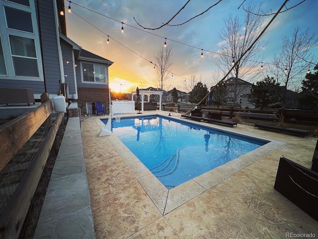 pool at dusk featuring a patio and a fenced in pool