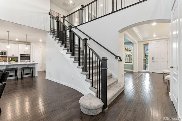 19894 W 94th Ln, Arvada, CO 80007 - entryway featuring arched walkways, dark wood-style floors, crown molding, stairway, and a high ceiling