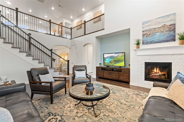 19894 W 94th Ln, Arvada, CO 80007 - living area featuring arched walkways, a high ceiling, wood finished floors, stairway, and a fireplace