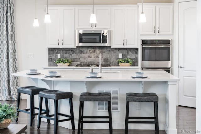 19894 W 94th Ln, Arvada, CO 80007 - kitchen featuring stainless steel appliances, backsplash, an island with sink, and light countertops