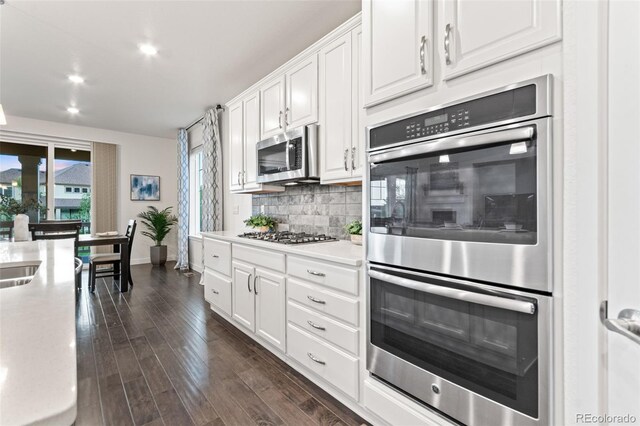 19894 W 94th Ln, Arvada, CO 80007 - kitchen with stainless steel appliances, white cabinets, tasteful backsplash, light countertops, and dark wood finished floors
