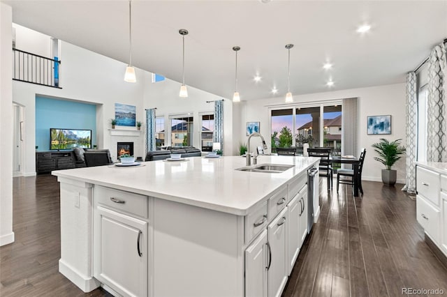 19894 W 94th Ln, Arvada, CO 80007 - kitchen with dishwasher, a glass covered fireplace, light countertops, dark wood-style floors, and a kitchen island with sink