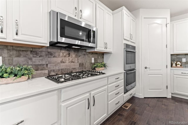 19894 W 94th Ln, Arvada, CO 80007 - kitchen featuring appliances with stainless steel finishes, white cabinetry, dark wood finished floors, and backsplash