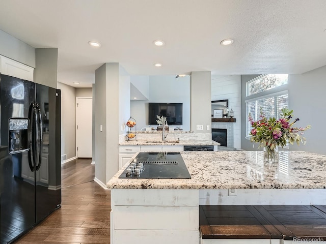 kitchen featuring light stone countertops, sink, dark hardwood / wood-style floors, white cabinets, and black appliances