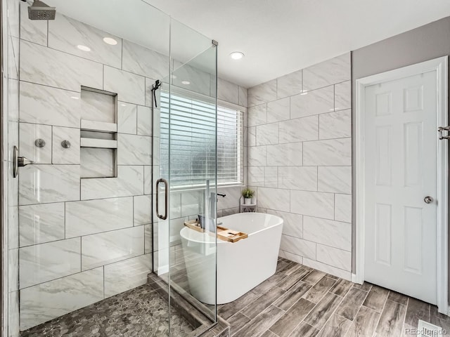 bathroom with hardwood / wood-style flooring, shower with separate bathtub, and tile walls