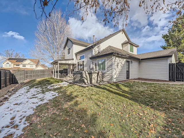 rear view of house featuring a patio area, a yard, and a hot tub