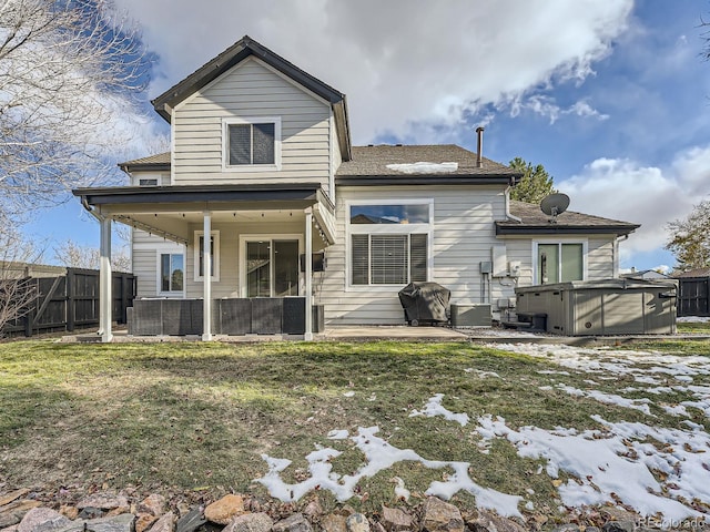 rear view of house with a lawn, a patio, and a hot tub