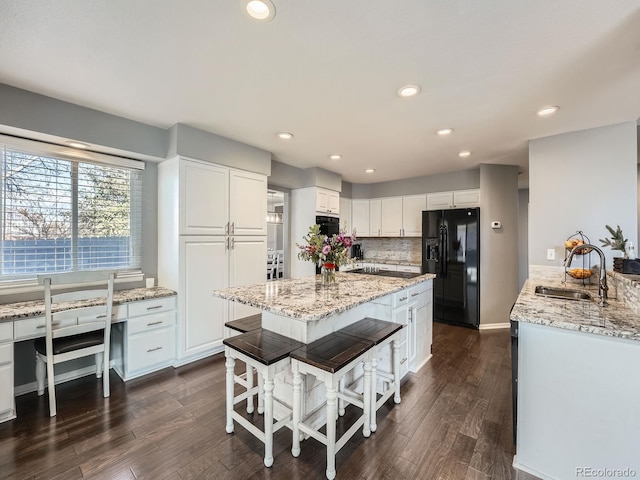 kitchen with light stone countertops, dark wood-type flooring, sink, black appliances, and white cabinetry