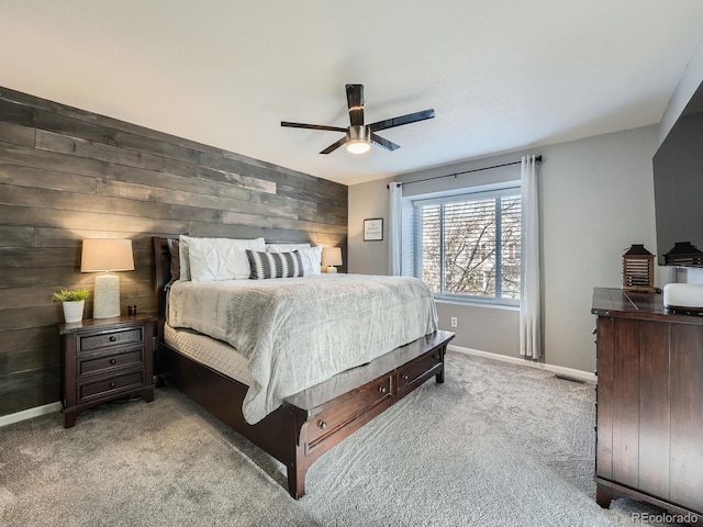 bedroom with ceiling fan, wood walls, and light colored carpet