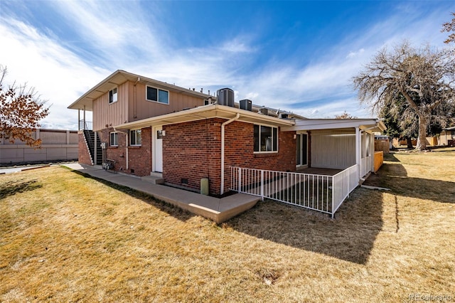 back of property featuring entry steps, a yard, and brick siding