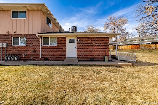 back of house featuring crawl space, a lawn, board and batten siding, and brick siding