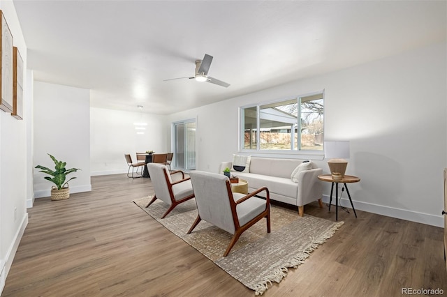 living room with ceiling fan, baseboards, and wood finished floors